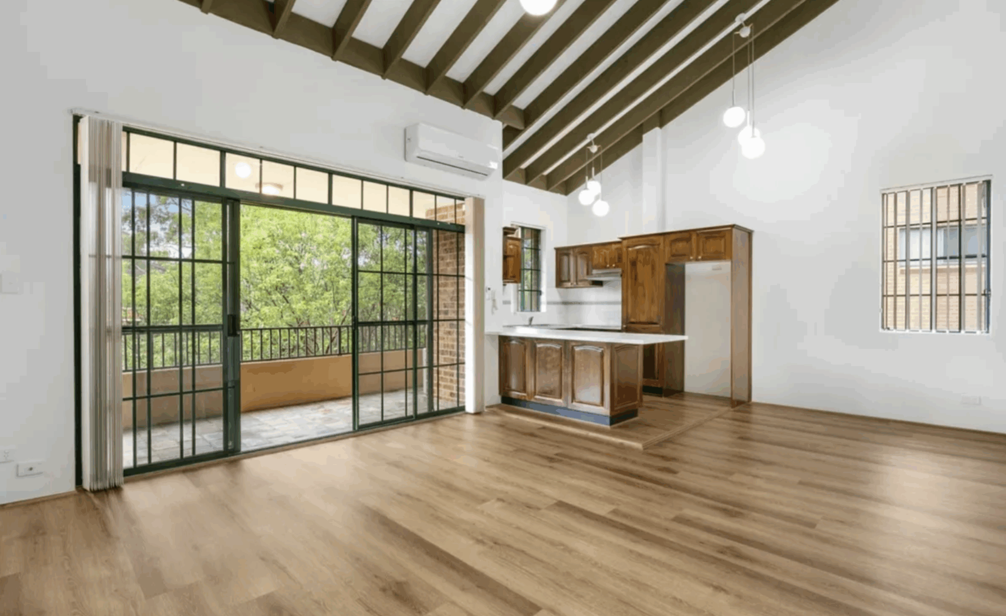 Spacious modern kitchen with wooden floors and large windows.